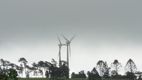Windkraftanlage-Bei-Stürmischem-Wetter-Mit-Bäumen-Und-Bewölktem-Himmel,-Breiter-Statischer-Schuss