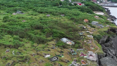 Aerial-pull-out-shot-away-from-Lambai-Island-coastal-Asian-Chinese-cemetery,-Xiaoliuqiu,-Pingtung-county,-Taiwan