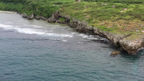 Aerial-drone-hovering-around-the-coastal-rocky-shore,-pan-up-reveals-beautiful-horizon-in-Xiaoliuqiu-Lambai-Island,-Pingtung-county,-Taiwan