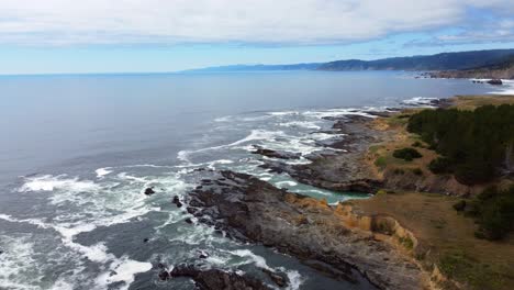 Static-drone-shot-of-ocean-waves-crashing-against-oceanside-rock-formations---4K-30FPS-Aerial-Drone-Footage-of-the-Oregon-Coast