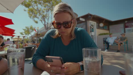 Caucasian-woman-playing-on-cell-phone-while-outdoor-dining