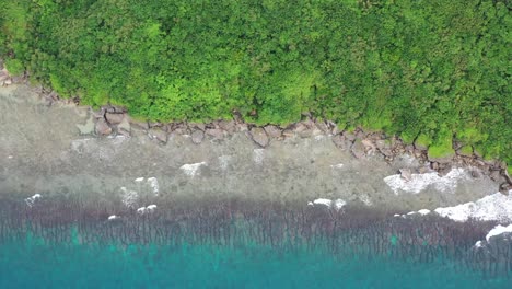 Aerial-straight-down-view-capturing-beautiful-turquoise-sea-water-with-waves-crashing-the-shore-reveals-sea-god-temple-at-black-dwarf-cave-at-Xiaoliuqiu-Lambai-Island,-Taiwan