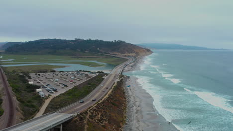 Aerial-flying-backwards-over-Torrey-Pines-State-Beach-on-cloudy-day