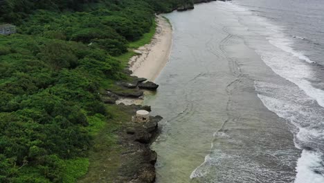 Aerial-drone-flying-forward-along-the-coastline-with-ocean-waves-hitting-the-rocky-shore-in-Xiaoliuqiu-Lambai-Island,-Pingtung-county,-Taiwan