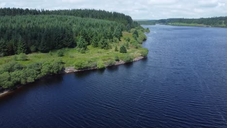 Idyllic-blue-water-reservoir-lake-woodland-hiking-walk-aerial-view-slow-reverse-descend