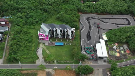 Aerial-ascending-top-down-view-overlooking-at-modern-contemporary-style,-cat-inspired-accommodation-building-exterior-and-go-kart-raceway-at-Xiaoliuqiu-Lambai-Island,-Pingtung-county,-Taiwan