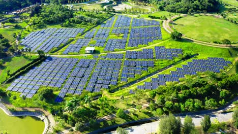 Aerial-flyover-photovoltaic-plant-farm-during-bright-sunny-day-surrounded-by-green-grass-field