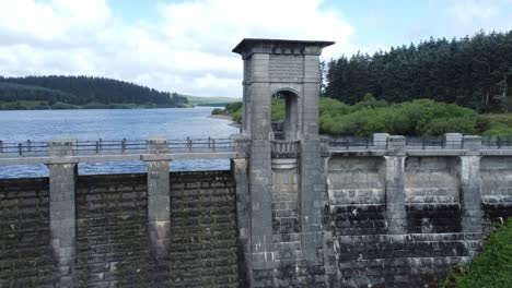 Alwen-reservoir-Welsh-woodland-lake-water-supply-aerial-view-concrete-dam-countryside-park-rising-tilt-down-shot