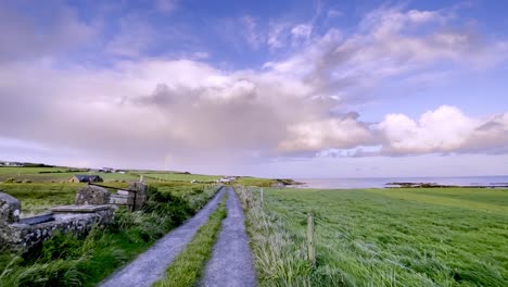 Farmland-in-west-Cork,-near-Kinsale,-Ireland-with-dramatic-cloud-and-rainbow-in-the-sky