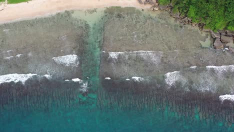Top-down-tracking-shot-capturing-Houshi-Fringing-Reef-and-beautiful-turquoise-sea-water-with-waves-crashing-the-shore-at-black-dwarf-cave-at-Xiaoliuqiu-Lambai-Island,-Taiwan