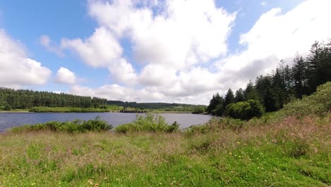 Sunny-Alwen-reservoir-timelapse-fast-clouds-passing-over-vast-blue-woodland-lake-water-left-to-right