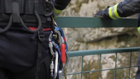 Closeup-of-firefighter-wearing-belt-with-safety-carabiners,-standing-on-the-bridge
