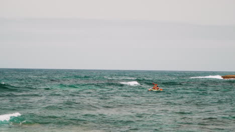 Slowmo-wide-shot-of-people-rowing-Paddle-On-A-paddle-Boat-during-waves-on-the-ocean