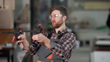 Cute-young-man-in-work-uniform-shoots-with-a-tool