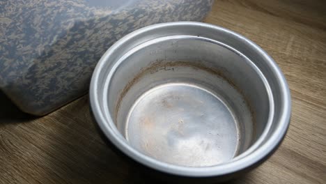 Empty-Rice-Cooker-kettle-and-three-cups-of-rice-being-poured-into-from-a-plastic-container