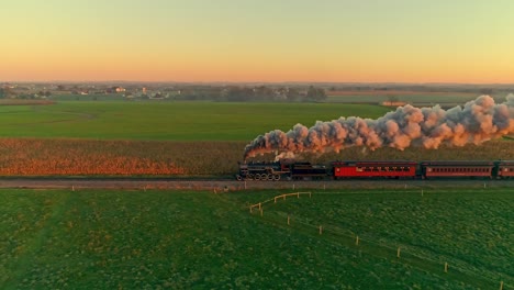 Aerial-View-of-a-Steam-Engine-and-Passenger-Cars-at-the-Golden-Sunrise-with-a-Full-Head-of-Steam-and-Smoke-Traveling-Thru-the-Farmlands