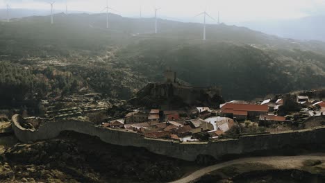Antigua-Ciudad-Medieval-Amurallada-Que-Se-Opone-A-Las-Turbinas-Eólicas-Modernas-En-Las-Escarpadas-Montañas-Nubladas