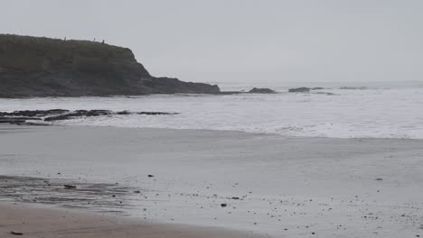 Cliffs-near-beach-are-fogged-up-and-hit-by-waves-during-stormy-winter-day