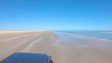 point-of-view-of-vehicle-roof-top-while-driving-on-a-nearly-deserted-beach-at-low-tide-on-South-Padre-Island,-Texas