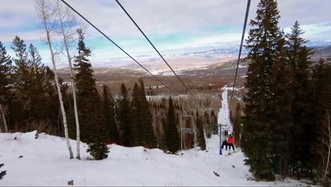 Schöne-Aussicht-Von-Einem-Skilift-In-Einem-Skigebiet-In-Colorado-An-Einem-Bewölkten-Wintertag-Mit-Hohen-Espen-Und-Kiefern-Mit-Atemberaubender-Wüstenorange-Und-Roter-Landschaft-Im-Hintergrund