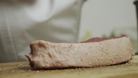 Adding-spice-onto-meat-steak-on-cutting-board