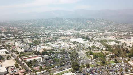 Aerial-dolly-backwards-looking-at-the-town-of-Santa-Barbara-with-shopping,-palm-trees-and-car-parks