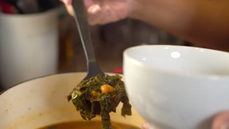 Scooping-a-ladle-of-kale-and-chickpea-soup-into-a-serving-bowl---close-up