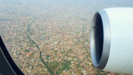 Close-up-of-airplane-engine-from-window,-during-landing-over-city