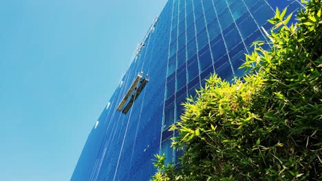 Window-cleaning-workers-on-a-high-swing-stage-suspended-scaffold-off-an-office-corporate-building