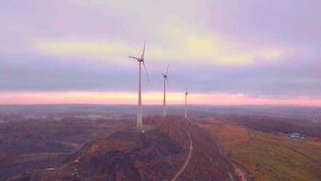 Aerial-shot-of-wind-turbine-farm-on-hill-during-sunset-in-background