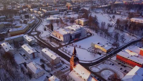 Beautiful-drone-shot-flying-over-the-city-of-Valmiera,-Latvia-in-winter,-with-a-view-of-the-St