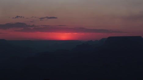 Bright-red-sunset-disappearing-behind-a-dark-nighttime-Grand-Canyon,-Arizona