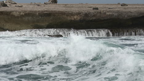 Waves-breaking-on-rocks,-creating-waterfalls,-Bonaire
