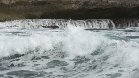 Waves-breaking-on-rocks,-creating-waterfalls,-Close-up,-Bonaire