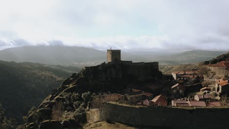 Castillo-Medieval-Aislado-En-La-Cima-De-Una-Colina-Detrás-De-Los-árboles,-Revelando-Una-Toma-Aérea