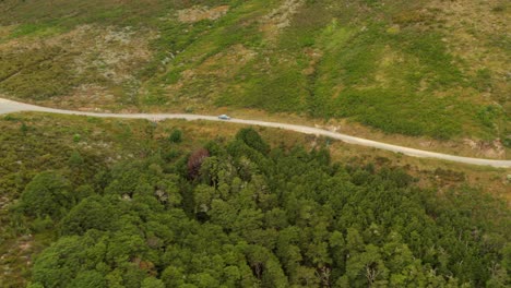 Drone-tracking-shot-of-a-car-driving-on-a-road-in-a-valley-of-New-Zealand