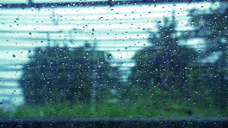 Regentropfen-Auf-Fenster-Mit-Verschwommenen-Bäumen-Als-Hintergrund-Während-Des-Regnerischen-Tages-In-Bangkok,-Thailand---Nahaufnahme