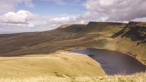 Time-lapse-of-rural-lake-in-Brecon-Beacons-National-Park-and-yellow-mountains-with-cloudscapes-in-motion