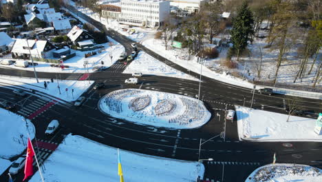 Cars-driving-on-black-asphalt-true-a-traffic-light-on-a-roundabout-in-the-city-Gdansk-Poland-on-a-cold-sunny-winter-day