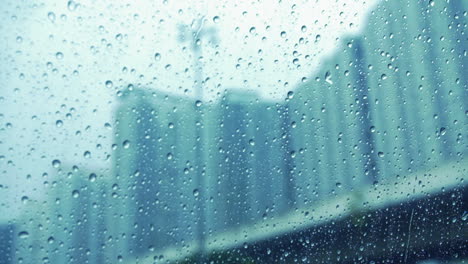 Raindrops-On-Glass-Surface-Window-With-Blurry-Cityscape-Background---close-up