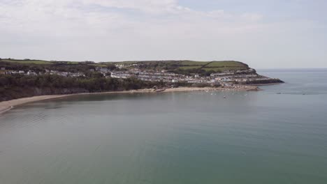 Aerial-lowering-drone-shot-of-New-Quay-harbour-and-beach,-Wales