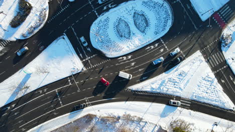 Aerial-view-drone-slowly-flying-over-a-complicated-multilane-circular-road-intersection-cleaned-from-the-snow-after-a-snowfall-in-Gdansk,-Poland