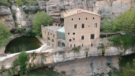 Vistas-Aéreas-De-Una-Cascada-Con-Una-Cueva-Y-Un-Edificio-Antiguo-En-Cataluña,-España