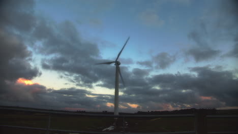 Lone-wind-turbine-spinning-against-golden-hour-cloudy-sky,-wide-angle