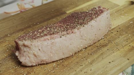 Adding-spice-onto-meat-steak-on-cutting-board