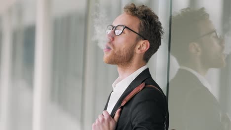 Stilvoller-Junger-Mann-Raucht-Eine-Elektronische-Zigarette-Im-Korridor-Des-Business-Centers