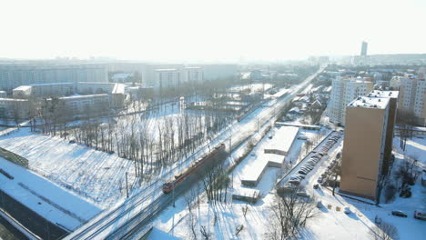 Aerial-view-of-local-Train-moving-across-the-bridge-in-winter-Gdansk,-Poland,-snow-covered-city-from-the-top