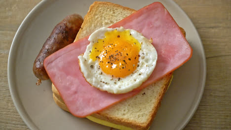 homemade-bread-toasted-cheese-topped-ham-and-fried-egg-with-pork-sausage-for-breakfast