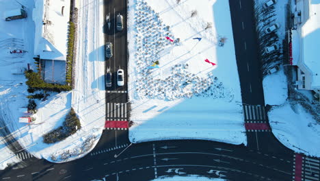 Top-down-view-of-downtown-Gdansk-covered-with-snow,-cars-waiting-for-the-green-light-on-the-road-intersection---aerial-top-hover-shot