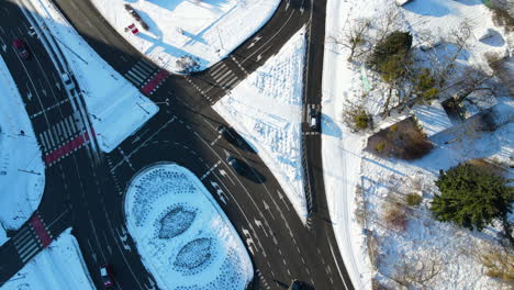 Aerial-view-drone-roll-over-a-complicated-multilane-circular-road-intersection-in-Gdansk,-Poland-on-a-winter-snowy-day